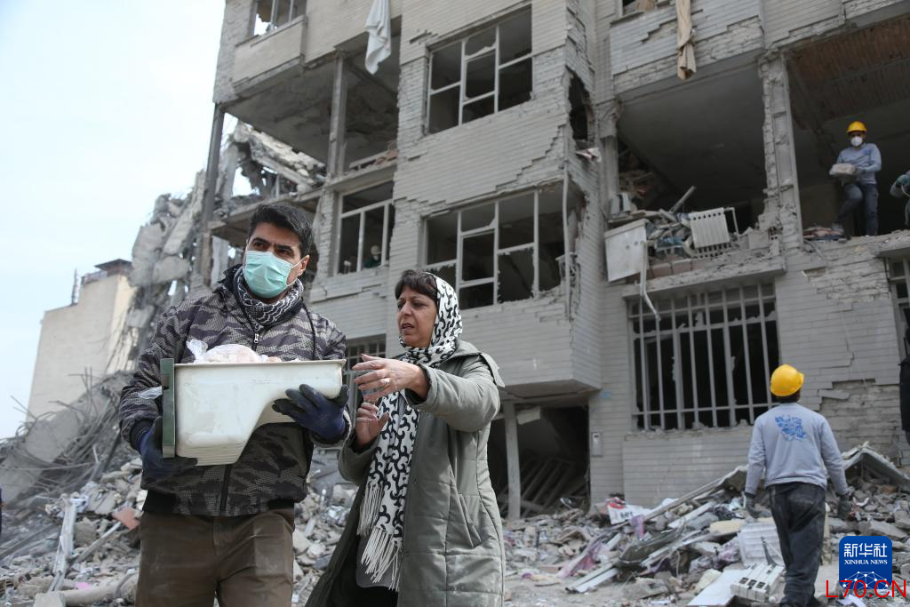 2026年3月12日，在伊朗首都德黑兰，市民站在建筑废墟前。 新华社记者 沙达提 摄